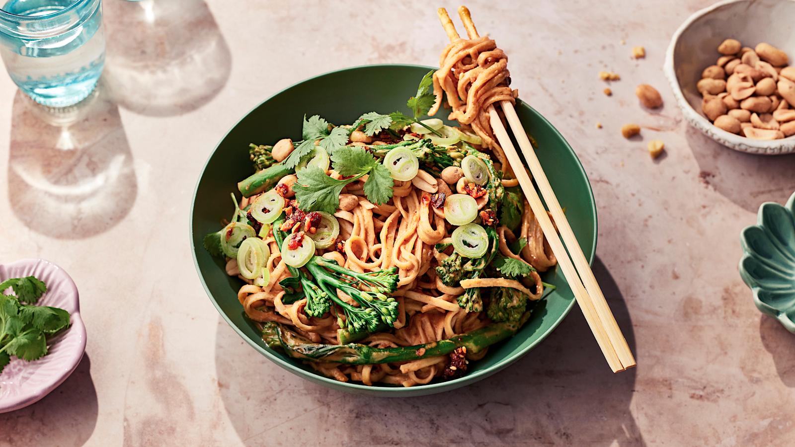 Maapähkinävoinuudelit kulhossa korianterilla koristeltuna. Kulhon reunalla syömäpuikot.