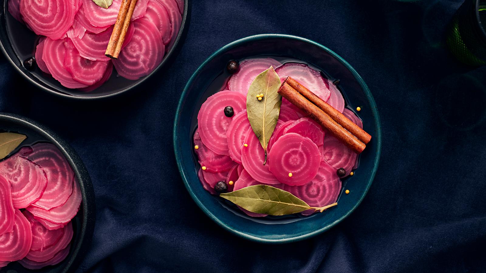 Pikkelöityjä raitajuuria kolmessa kulhossa. Raitajuurien päällä kanelitankoja, laakerinlehtiä ja pippureita.