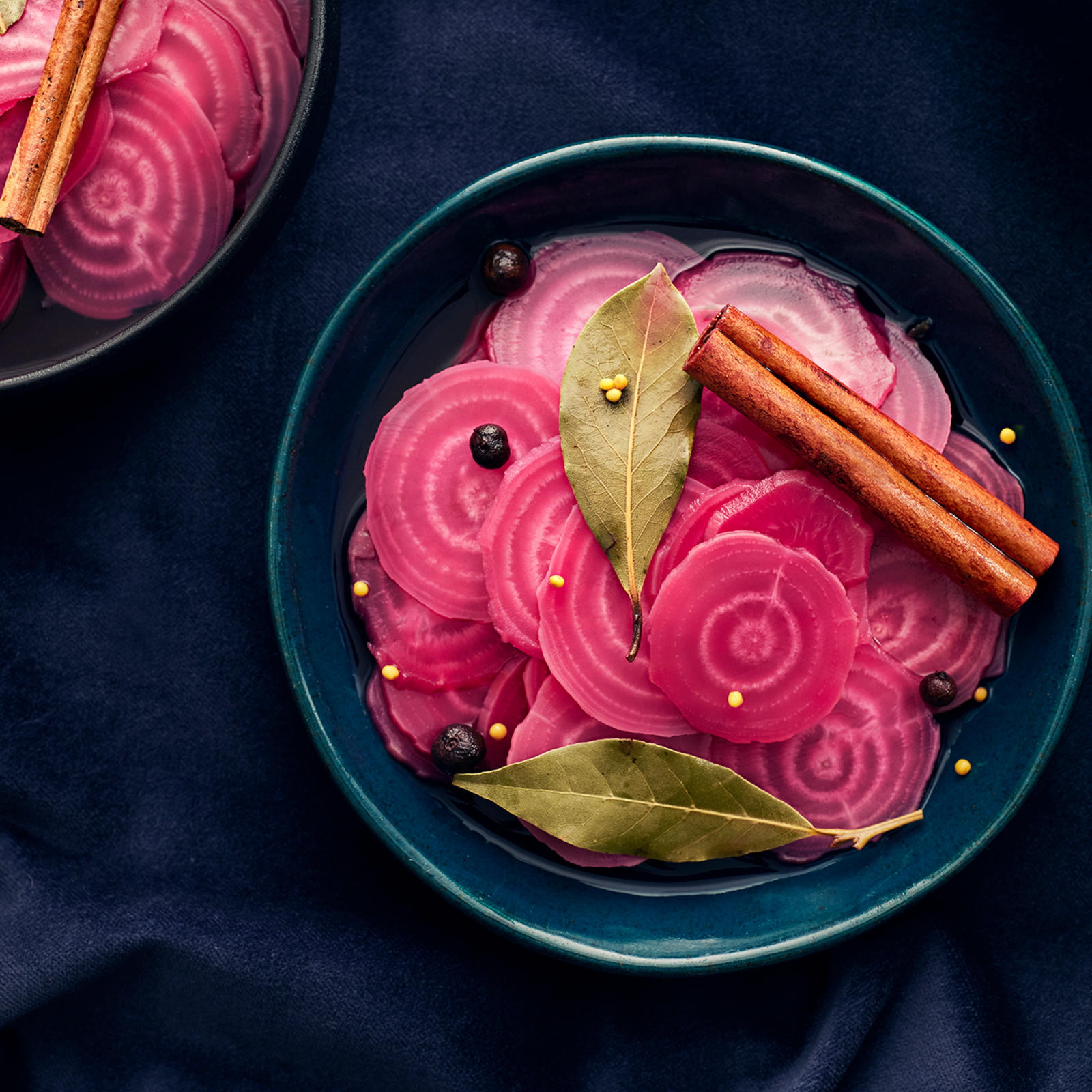 Pikkelöityjä raitajuuria kolmessa kulhossa. Raitajuurien päällä kanelitankoja, laakerinlehtiä ja pippureita.