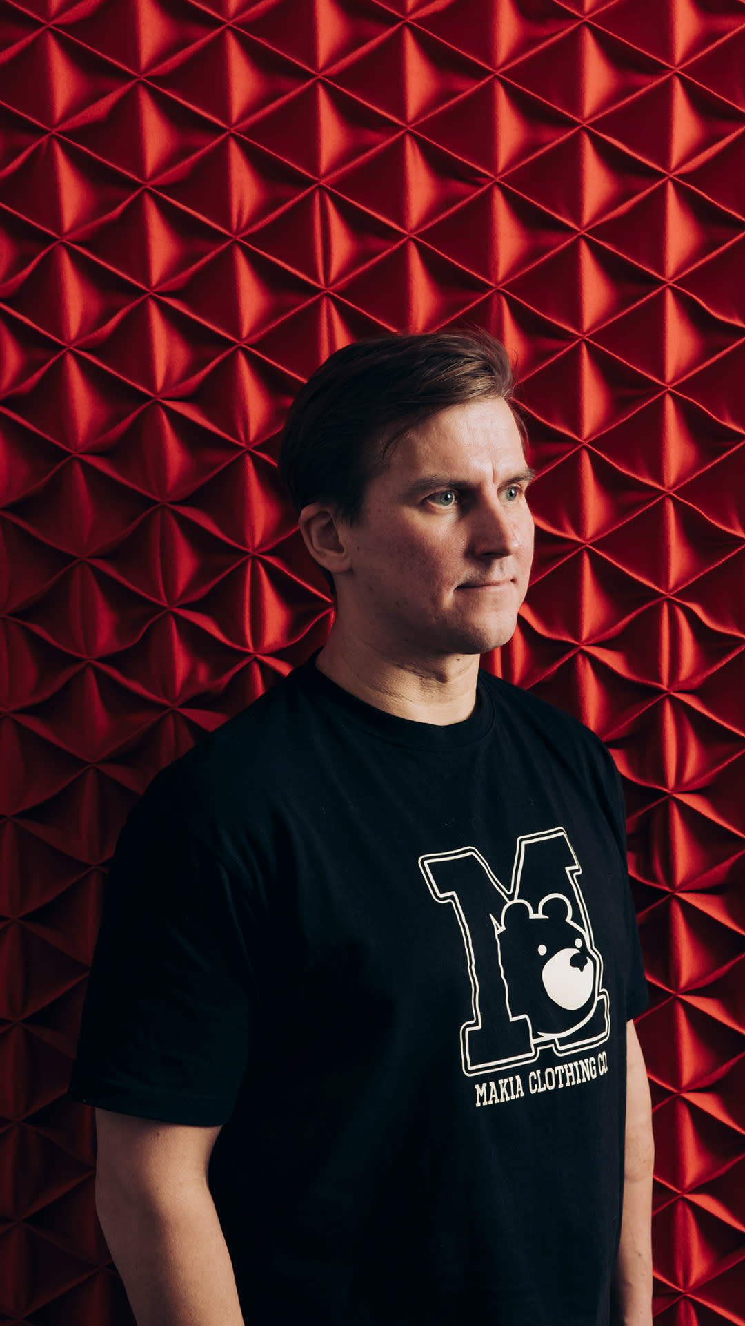 Makian perustaja Joni Malmi poseeraa punaisen seinän edessä.