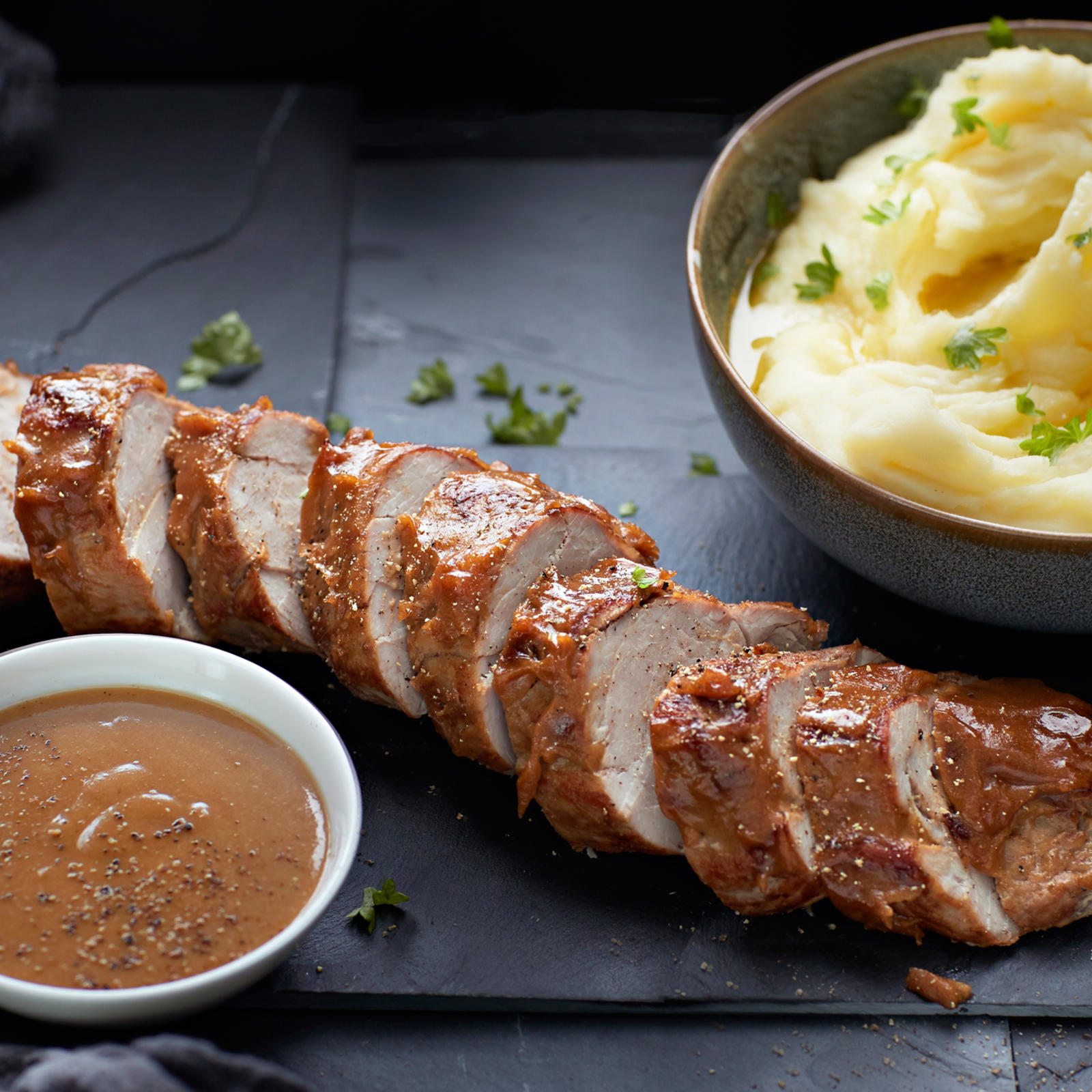 Porsaan sisäfilee viipaloituna ja kulhossa hedelmäinen kermakastike