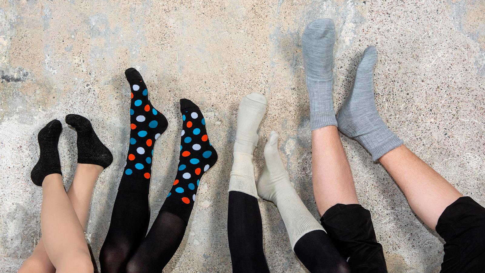 Neljä jalkaparia rivissä nostettuna seinää vasten erilaiset Sidoste-sukat jaloissa.