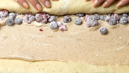 Lisää tuorejuustokerroksen päälle jäinen marja-perunajauhoseos. Rullaa taikina kääretortun tapaan tiiviiksi rullaksi. Leikkaa rulla terävällä veitsellä melko leveiksi paloiksi.