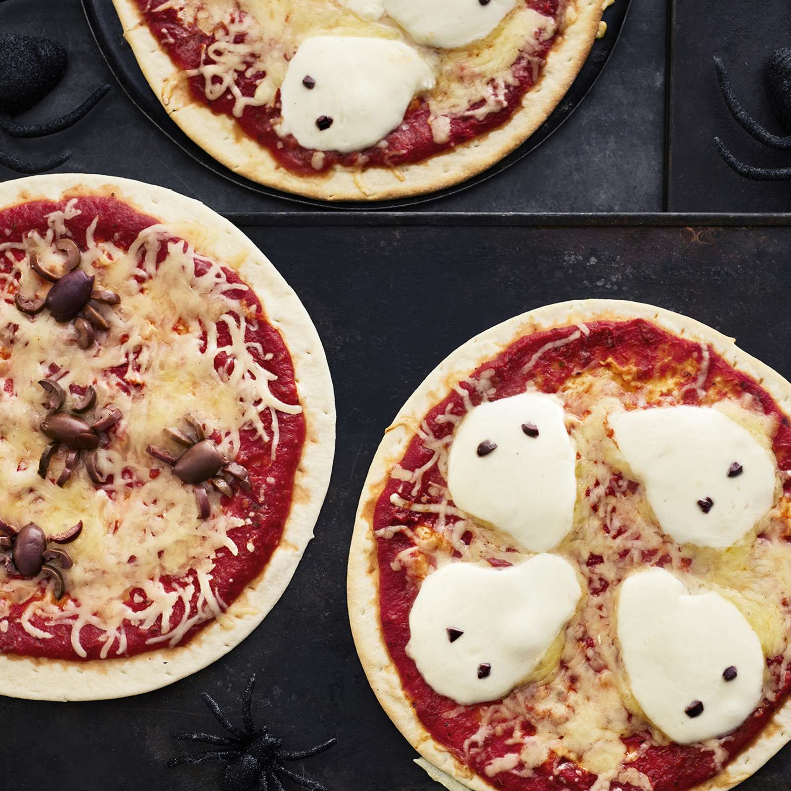 Halloweeniin sopivia pizzoja, joiden päälle asetellut oliivit muistuttavat hämähäkkejä ja mozzarellaviipaleet haamuja.