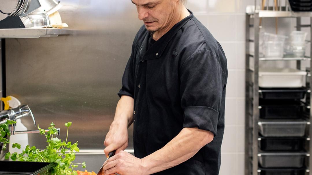 Teppo Vahtera pilkkoo vihanneksia kouluruokalan keittiössä.