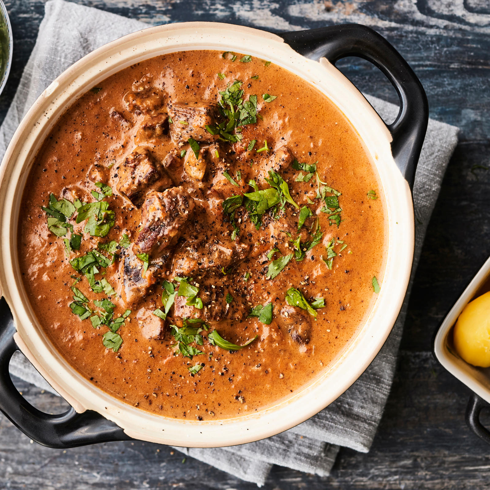 Palapaisti padassa. Vieressä keitettyjä perunoita ja hölskytyskurkkuja tarjoiluastioissa.