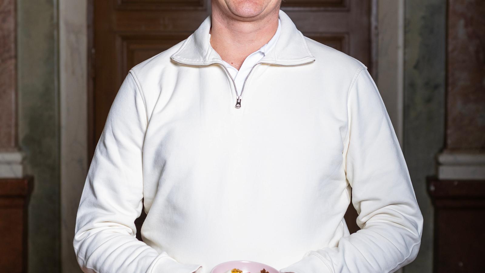 Samuli Wirgentius seisoo ja hymyilee. Kädessä on kuppi jäätelöä.