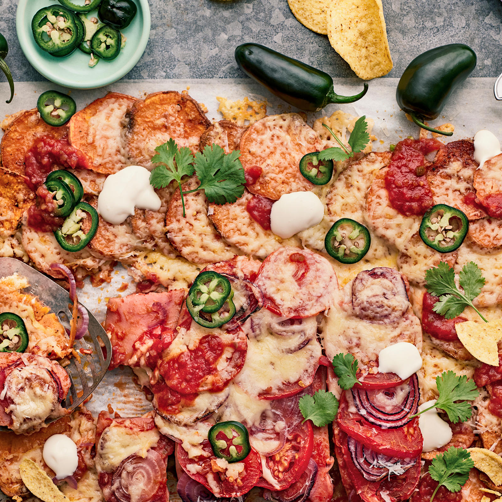 Texmex-uunimakkara bataatilla leivinpaperin päällä korianterilla ja jalapenoilla koristeltuna.