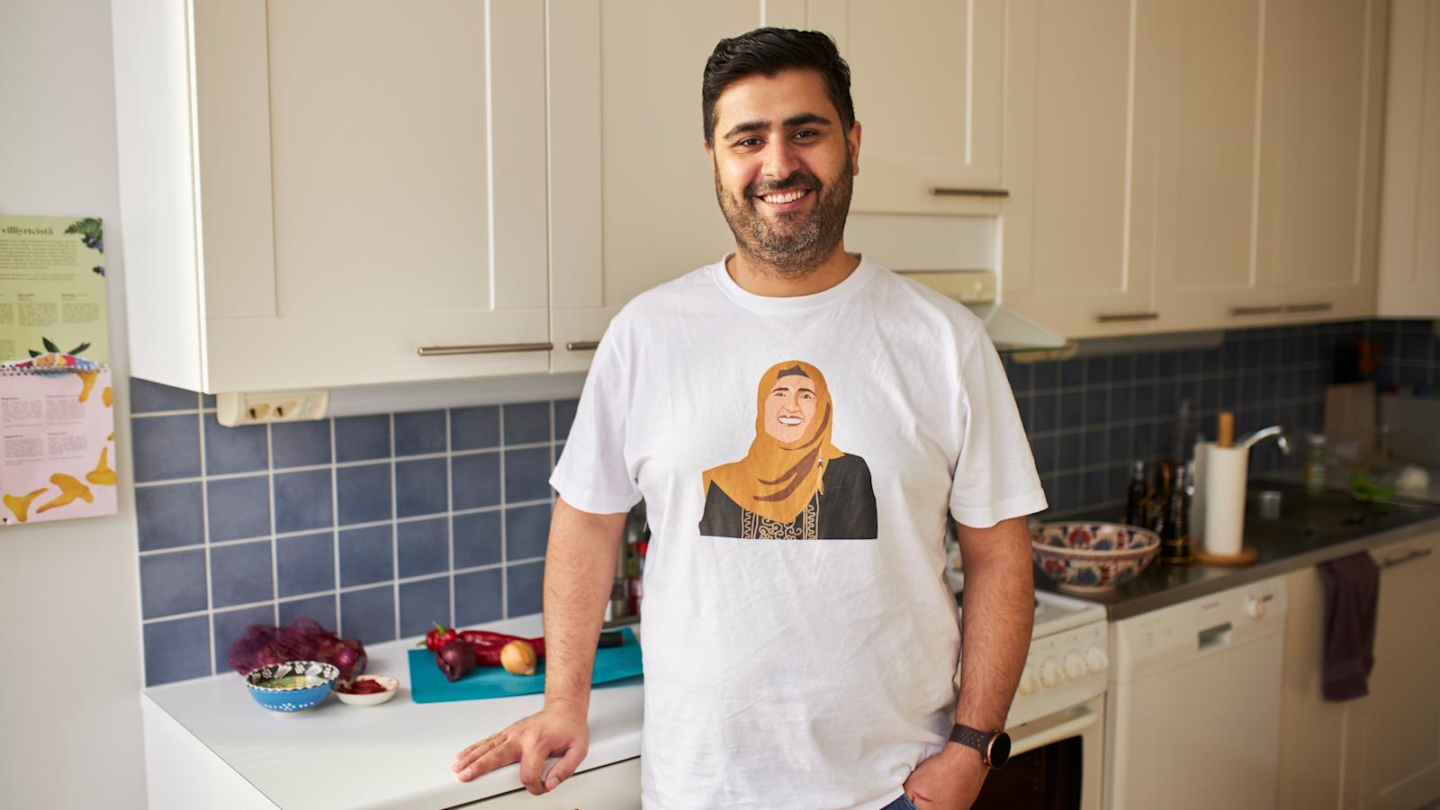 Siva Parlar seisoo keittiössään. Sivalla on t-paita, jossa on hänen äitinsä kuva.