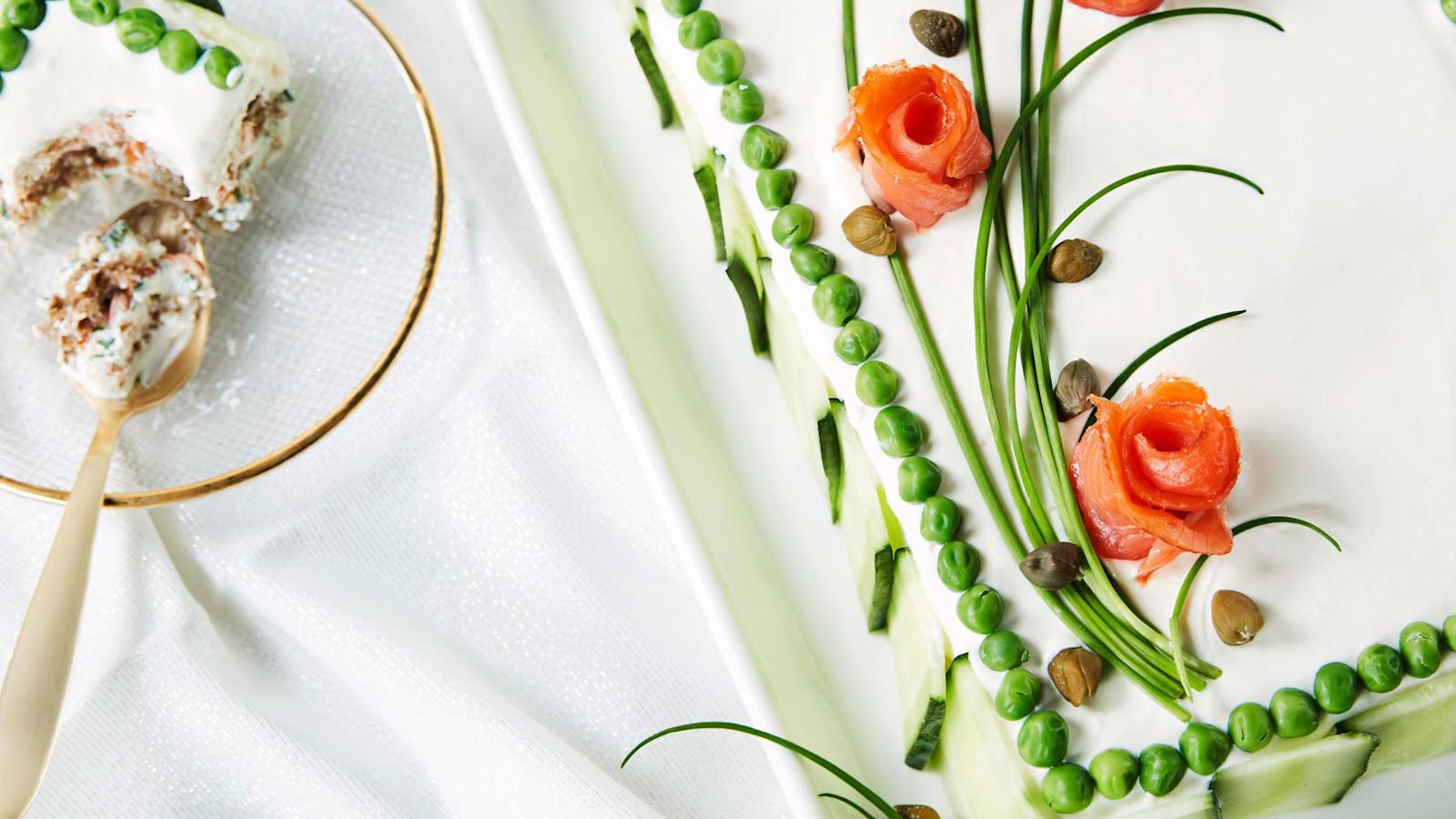 Kehystä kakun päällys sulaneilla pakasteherneillä. Pyöräytä kylmäsavulohiviipaleista ruusukkeita. Sommittele ruohosipulin varsista ja lohiruusuista kukkia kakun pinnalle. Lisää kapriksia nupuiksi.