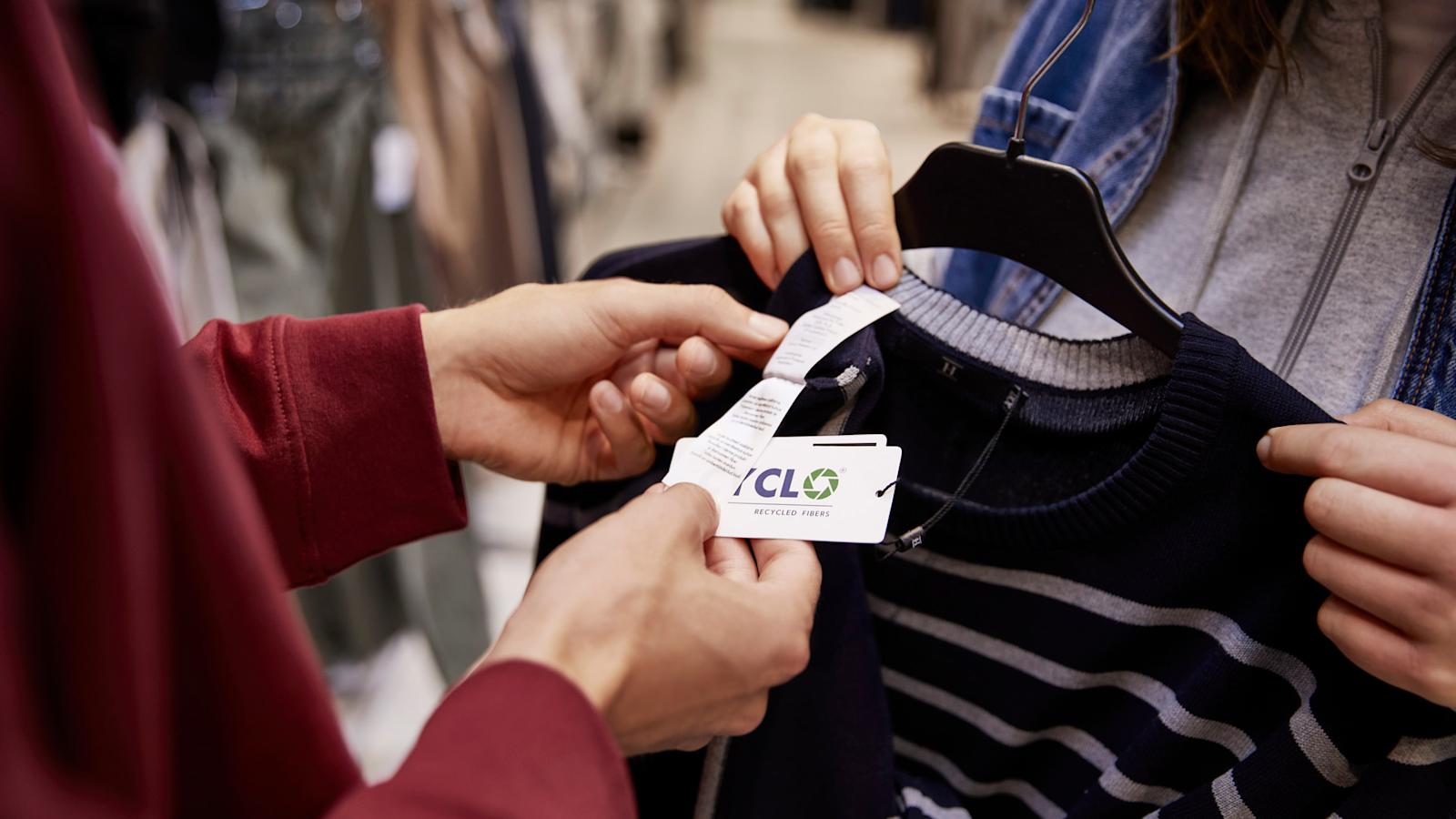 Kahdet käsiparit pitelevät villapaitaa, josta roikkuvassa tuotetietolapussa lukee cyclo.