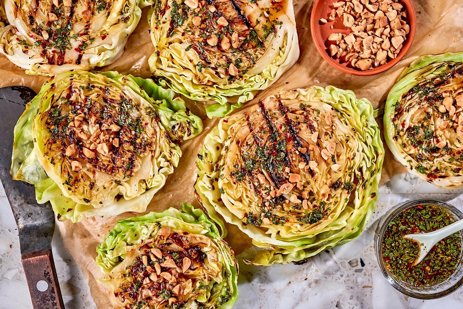 Grillattu varhaiskaali chili-sitruunakastikkeella. Vieressä paistinlasta sekä kastiketta ja suolapähkinöitä omissa kulhoissaan.