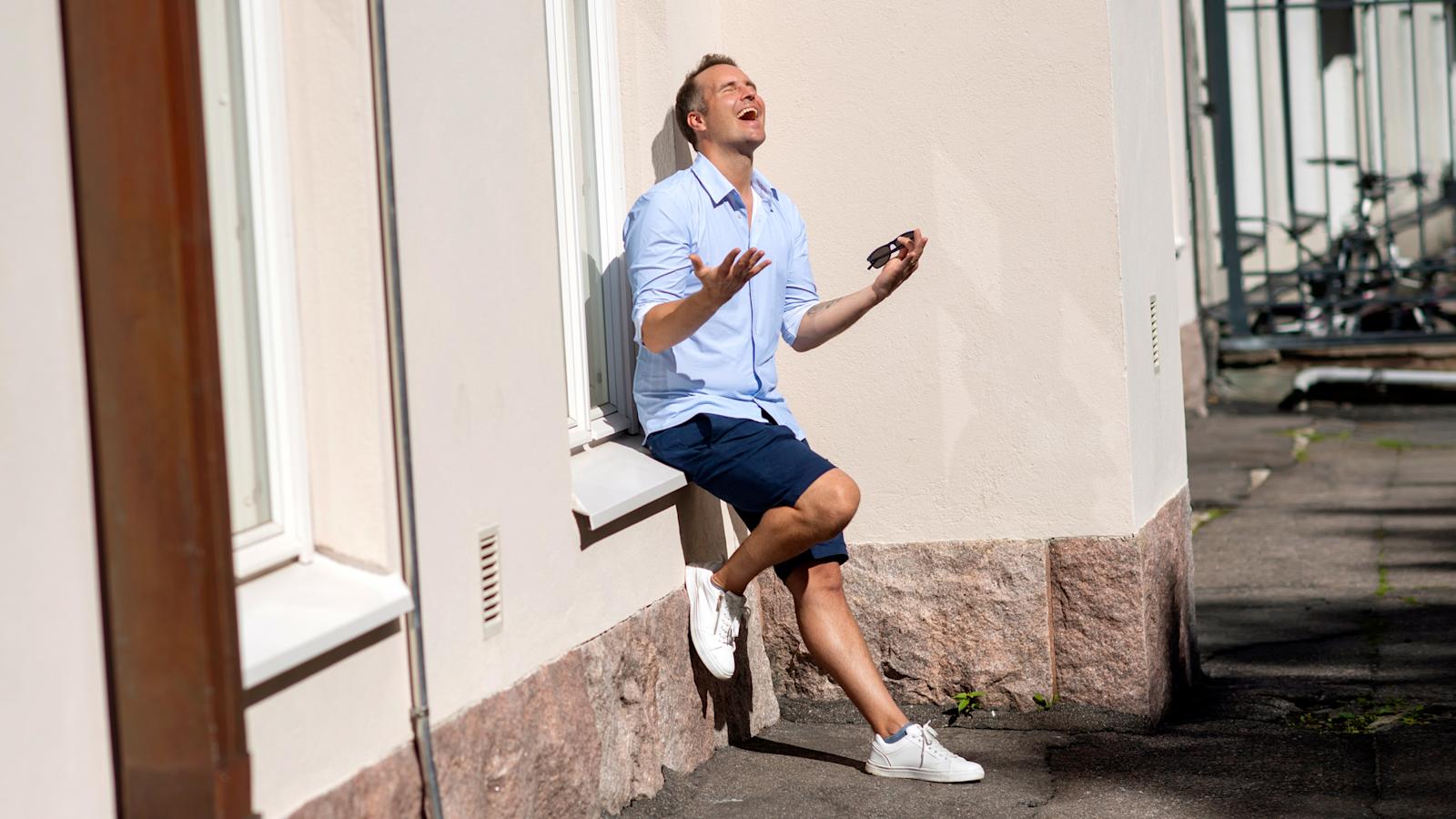 Mikael Forsby nojaa seinään. Aurinko paistaa ja hän on kohottanut kasvonsa kohti valoa.
