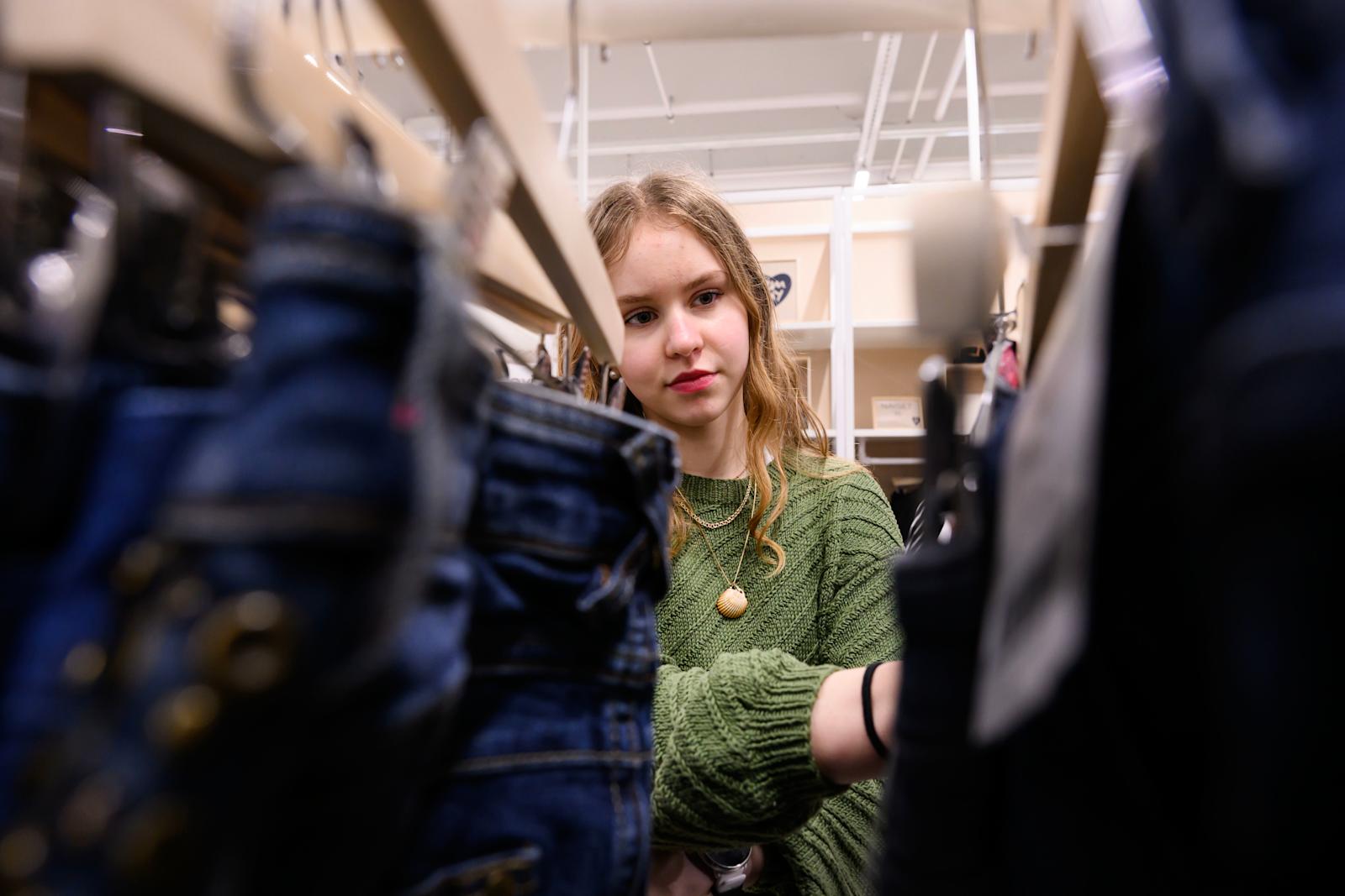 Tyttö katsoo käytettyjen farkkujen valikoimaa