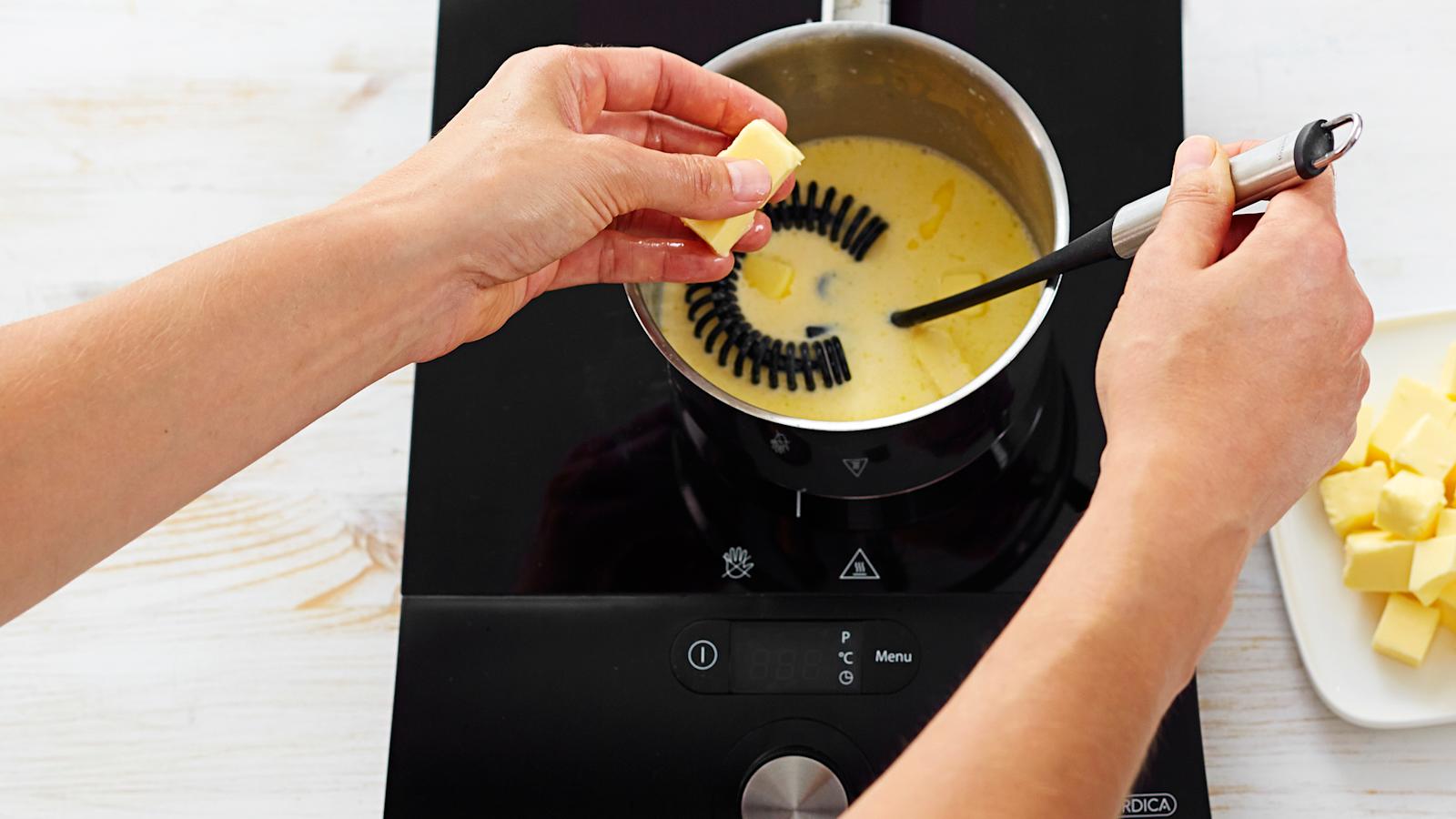 Ota kattila syrjään ja vatkaa joukkoon kylmä voi pieninä kuutioina. Lämmitä ja mausta.