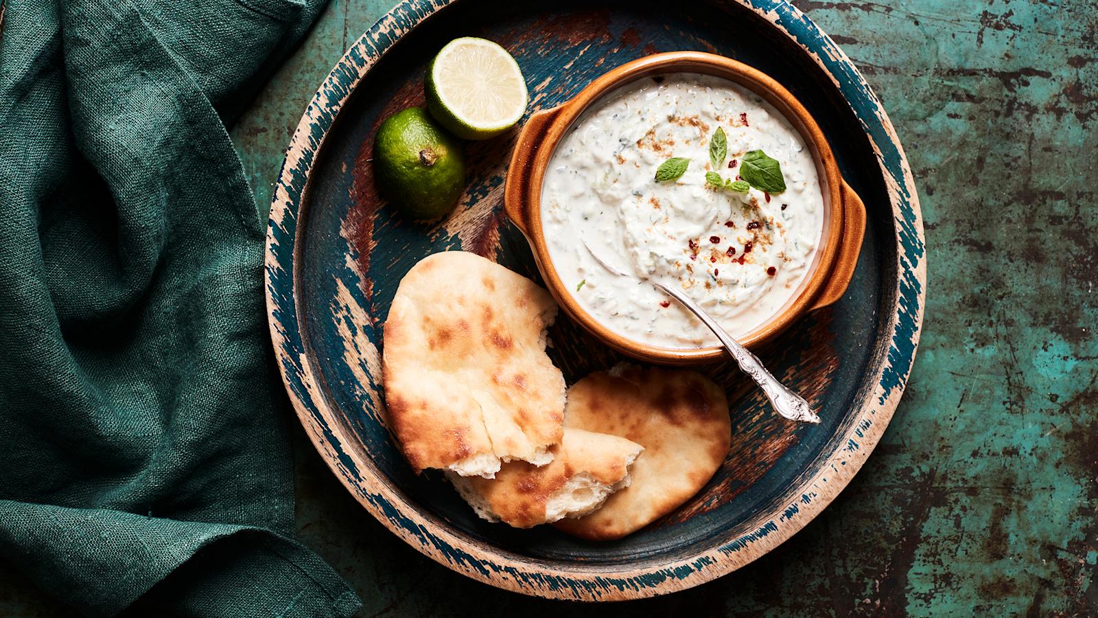 Raita-kastike kulhossa, vierellä naan-leipä
