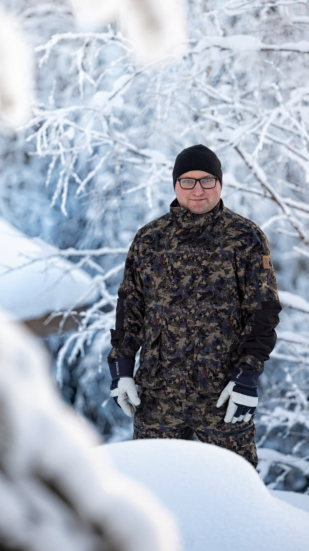 Niko Hämäläinen metsästysvarusteissaan lumisessa metsässä.