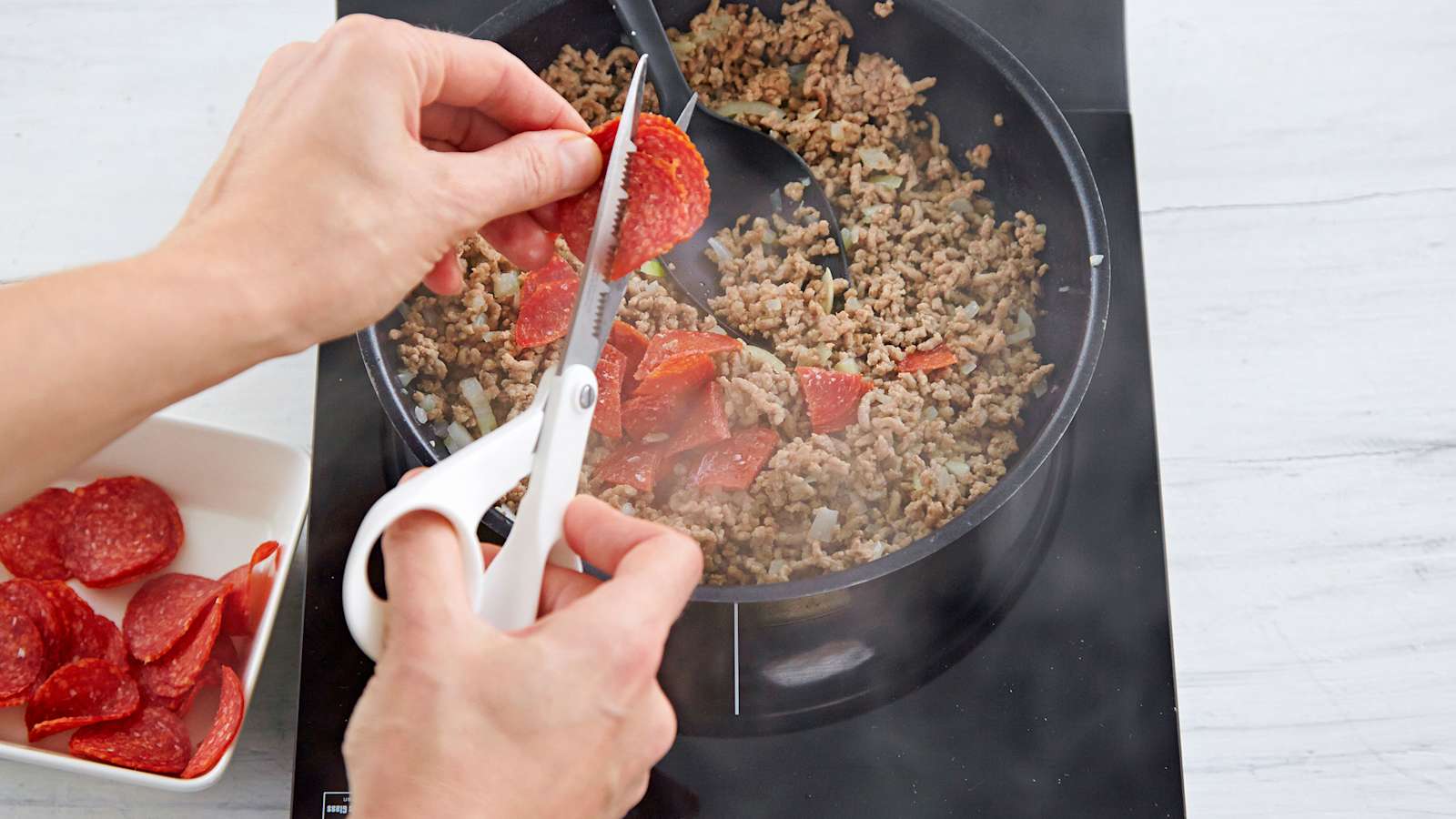 Kuori ja hienonna sipuli. Paahda pannulla jauheliha. Lisää sipuli. Saksi joukkoon pepperoniviipaleet.