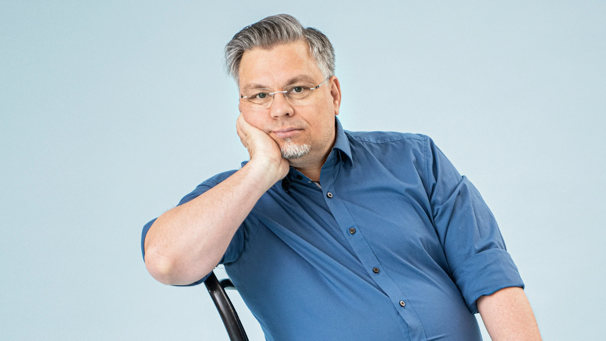 Tommi Kinnunen nojaa käteensä tuolilla istuessaan.