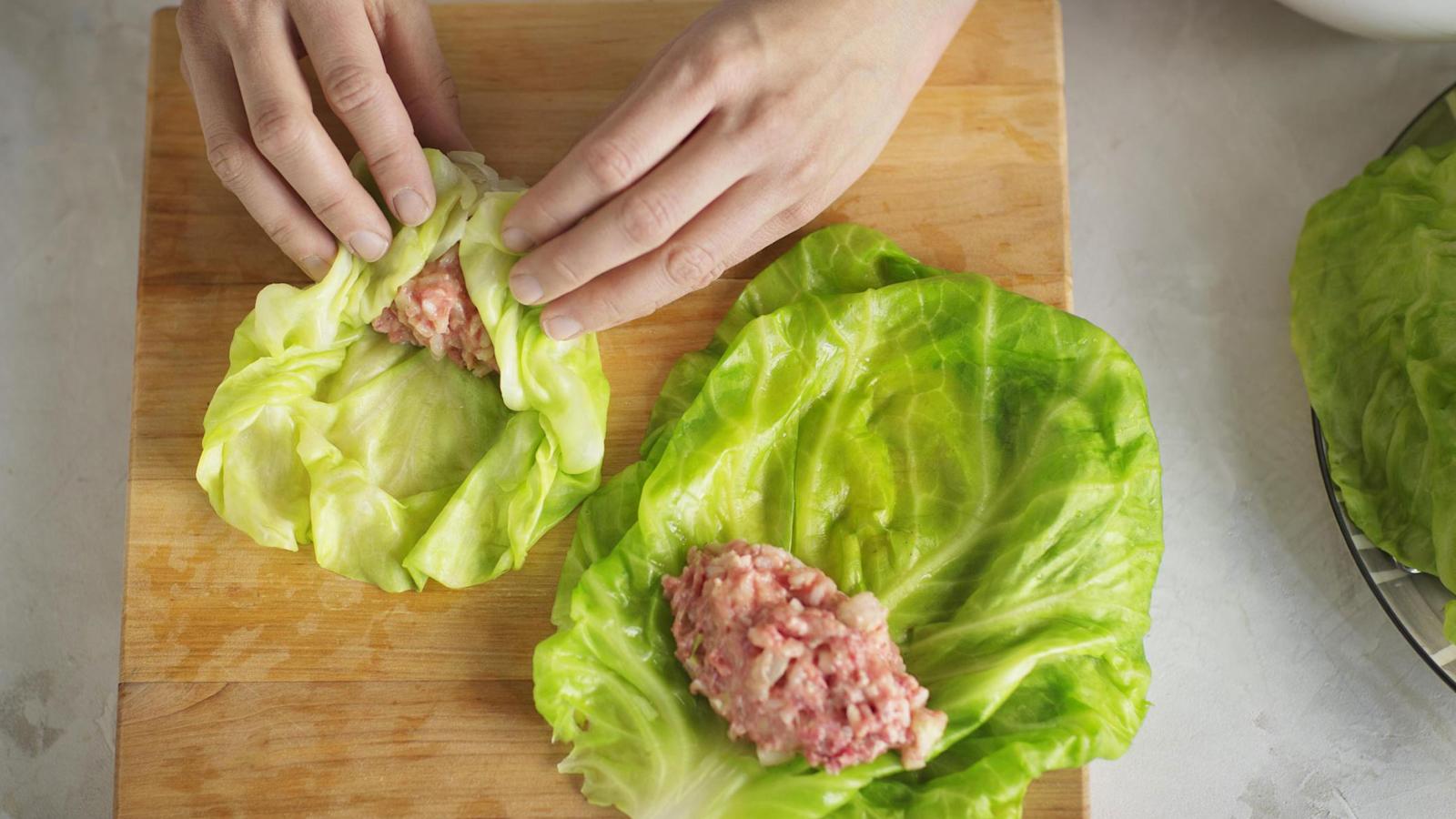 5\. Levitä lehdet työlaudalle. Nosta kullekin lehdelle reilu lusikallinen täytettä. Käännä ensin alareuna täytteen päälle, sitten reunat ja rullaa kääryleeksi. Asettele kääryleet vierekkäin uunivuokaan saumapuoli alaspäin.