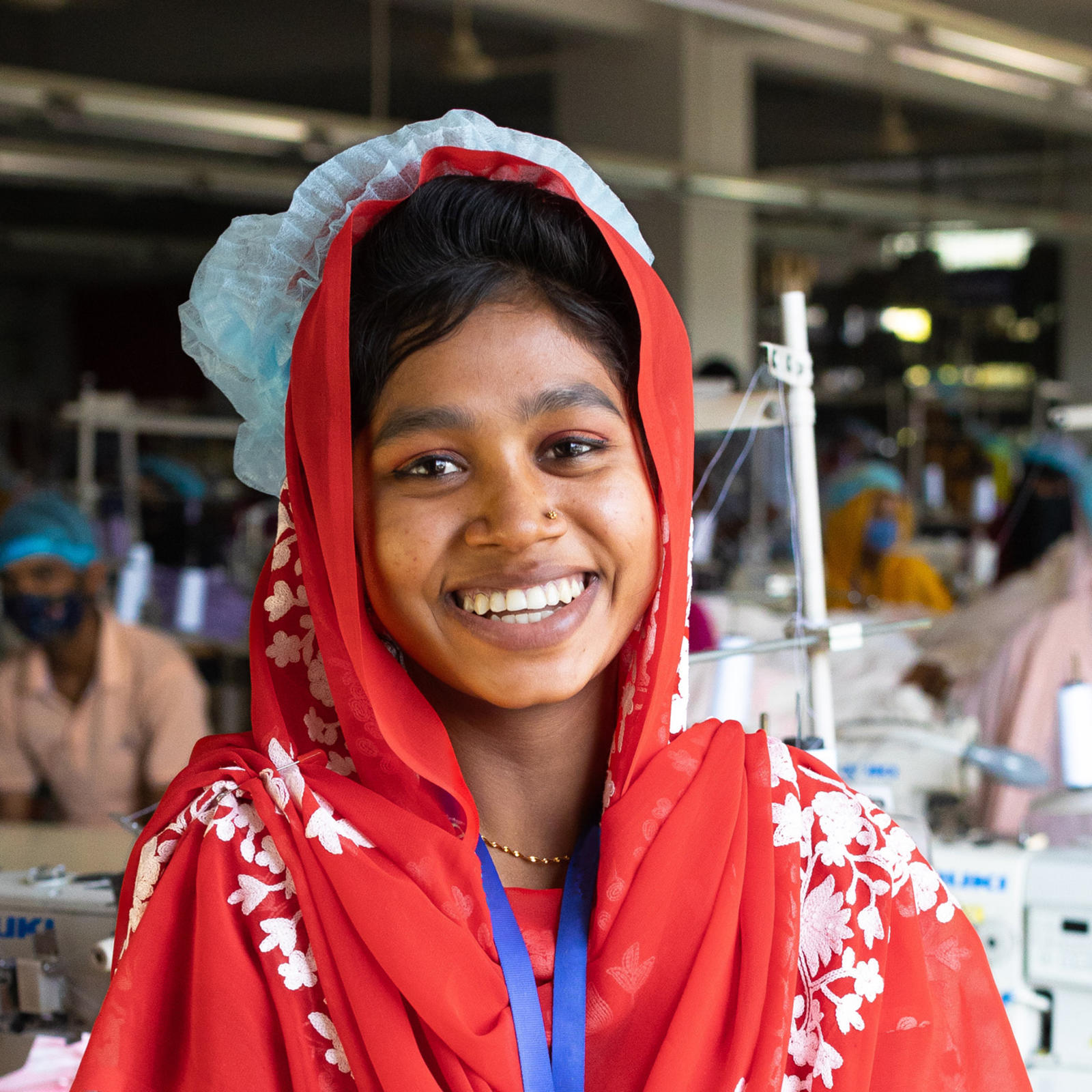 Vaatetehtaan työntekijä Tania Akter hymyilee kameralle.