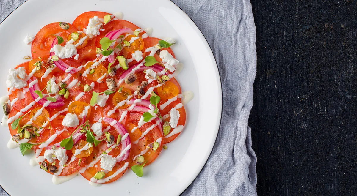 Tomaatti-vuohenjuustocarpaccio ja Kulman Keittiön pikkelöityä punasipulia