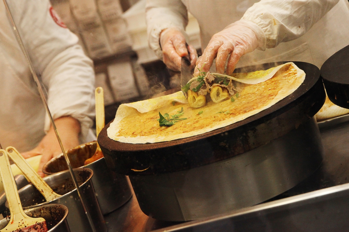 A chef prepares Jianbing, a savory breakfast crepe.