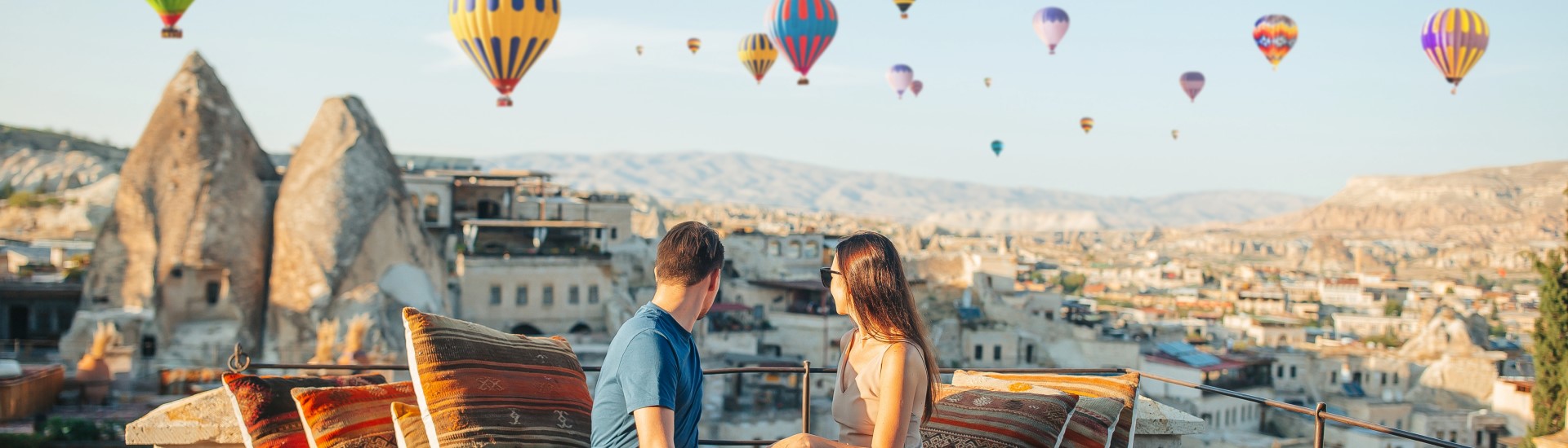 Couple watching hot air balloons during sunset in Cappadocia, Turkey