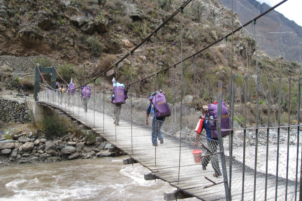 Porters on the Inca Trail to Machu Picchu crossing a bridge