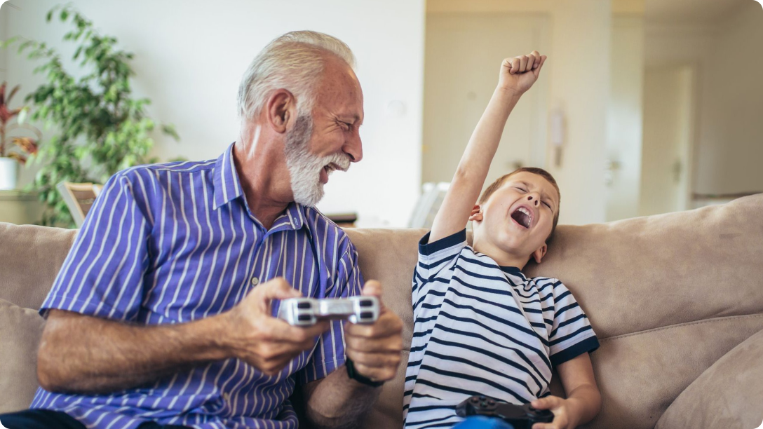 Grandpa and son playing a video game. The son is cheering.