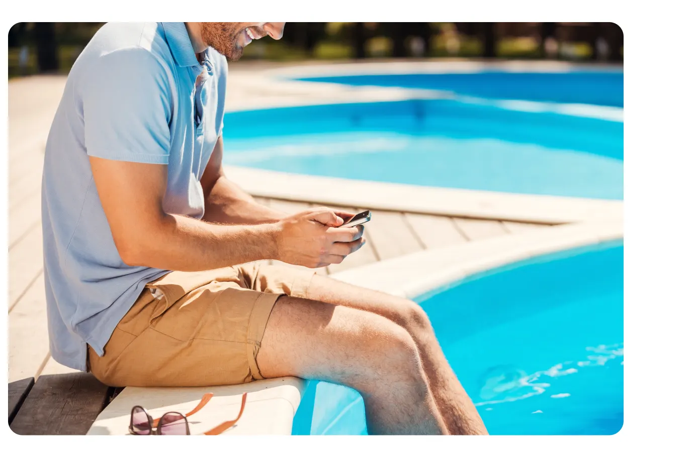 Sitting by pool using phone