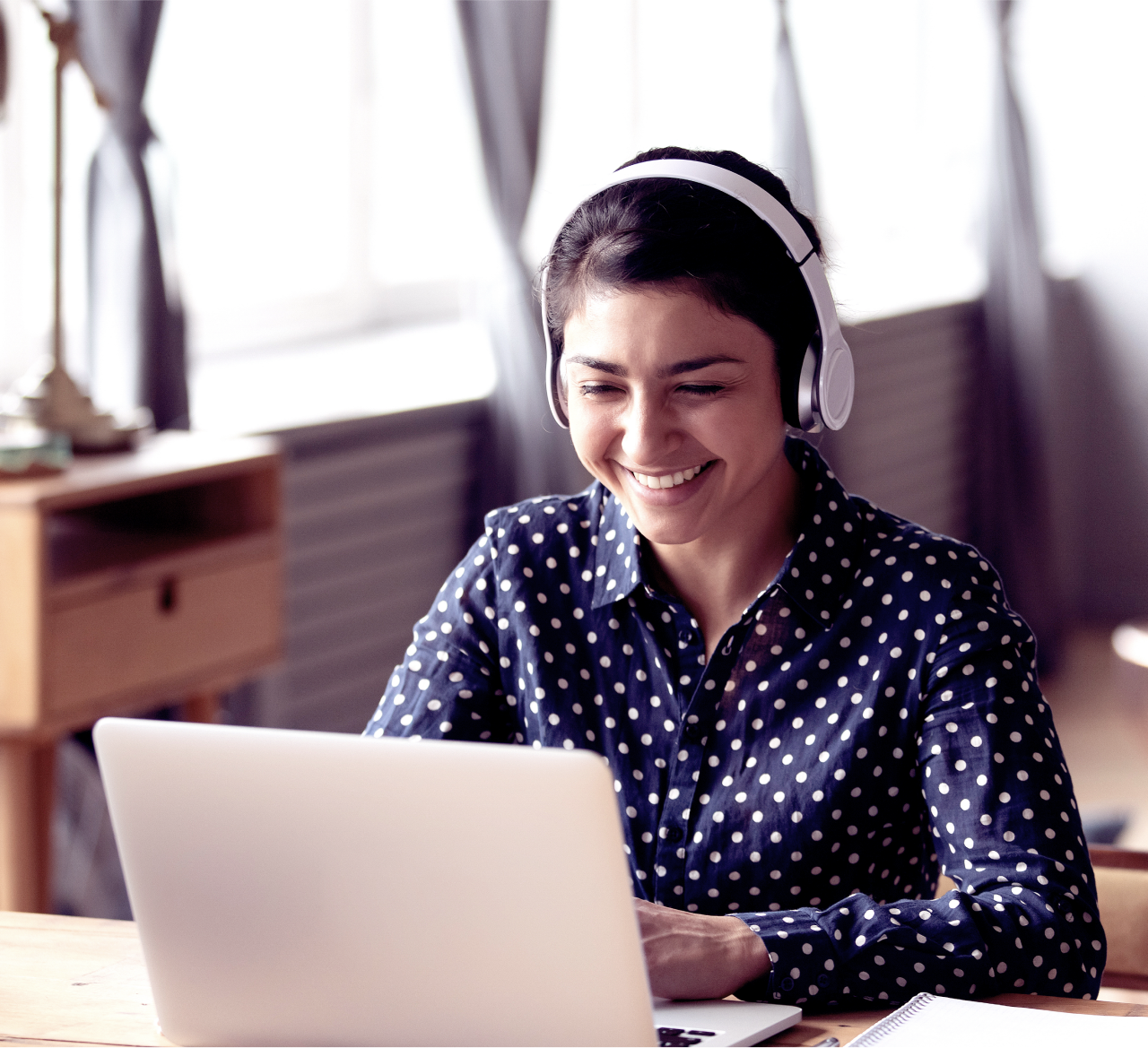 Woman working on laptop with headset in living room