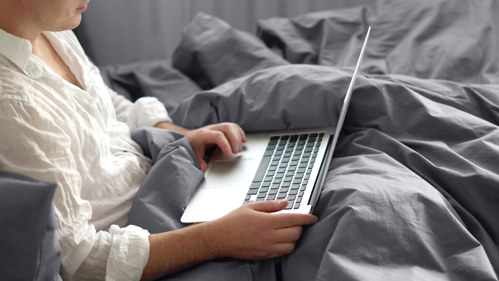 Person using MacBook on bed 