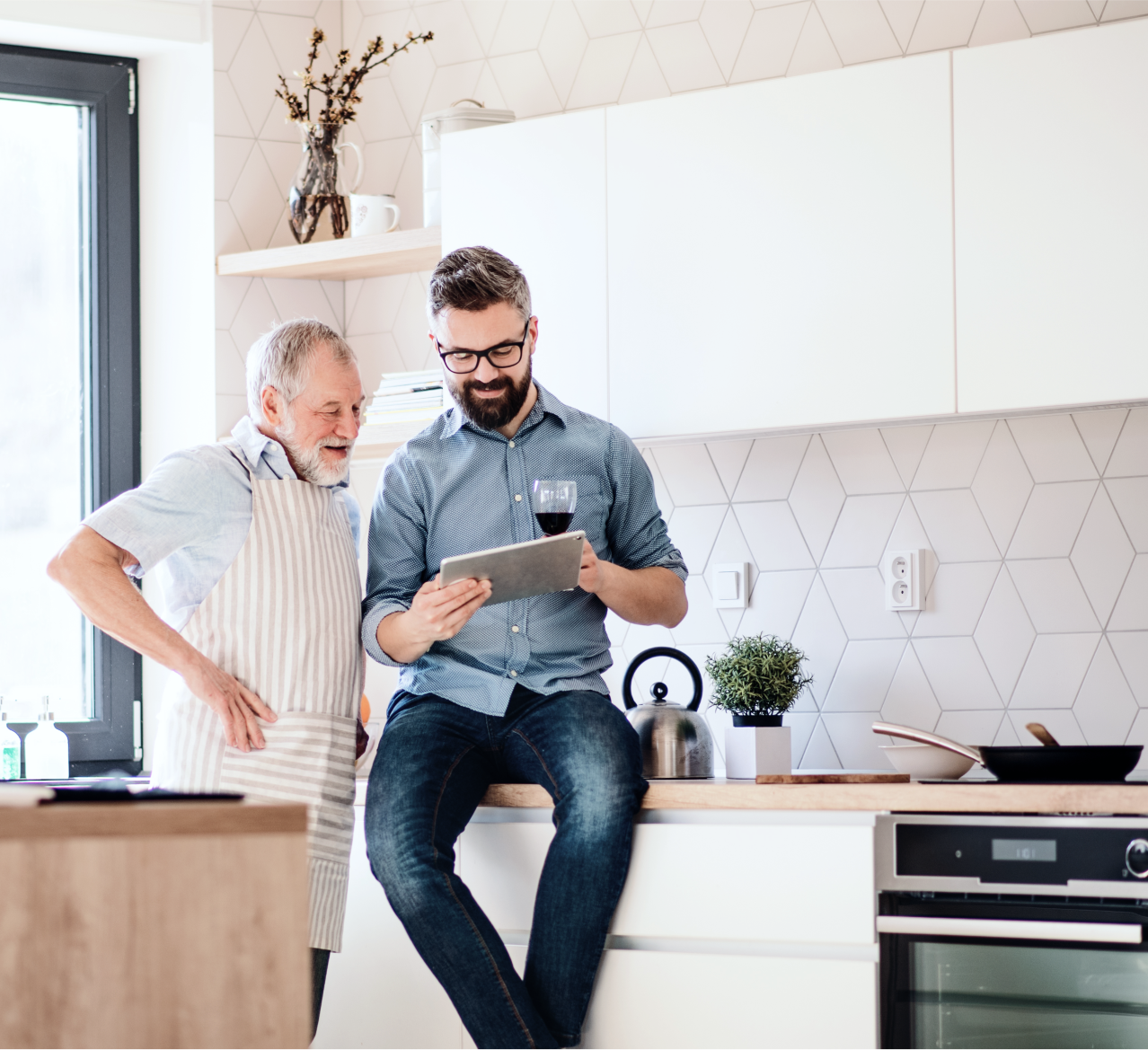 Adult father and son looking at tablet in kitchen