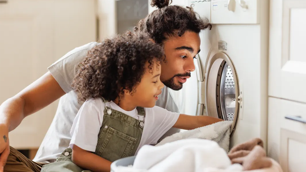 Father and son looking inside washing machine