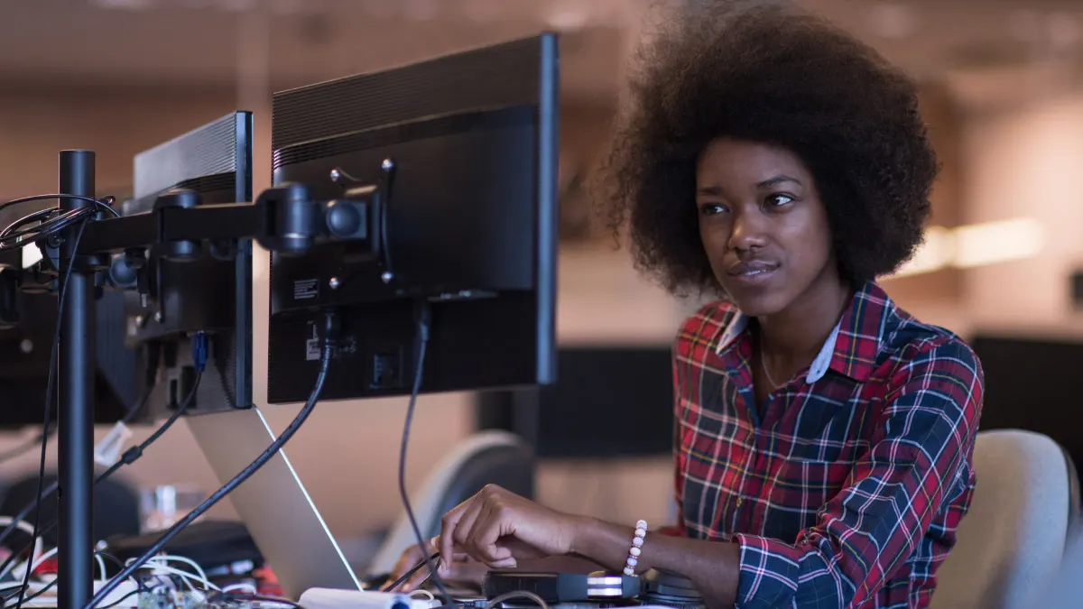 Woman working onMacBook Pro dual monitor