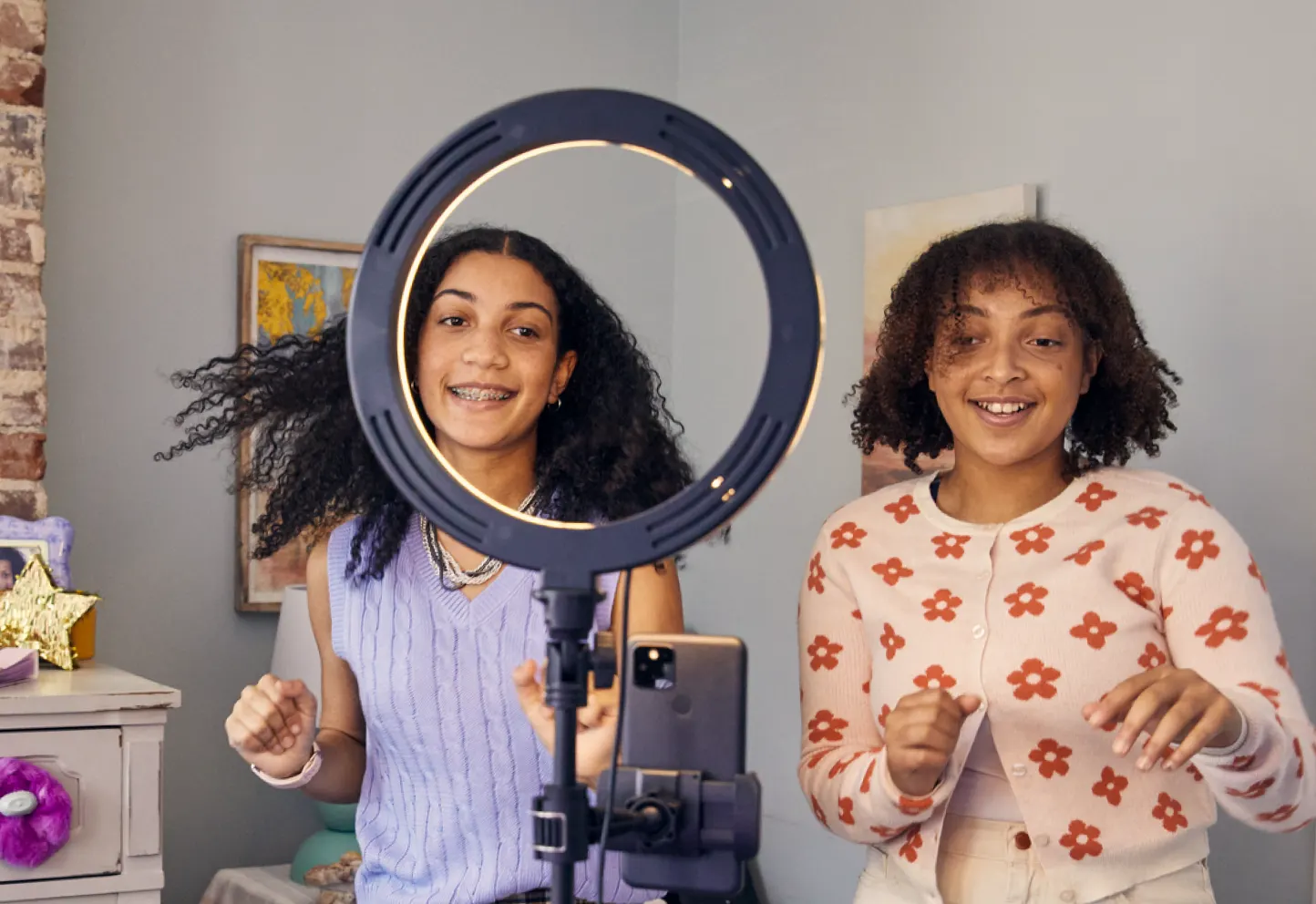 Two kids using a smart phone mounted with a circle light. Similar to how influencers record themselves in videos for social media