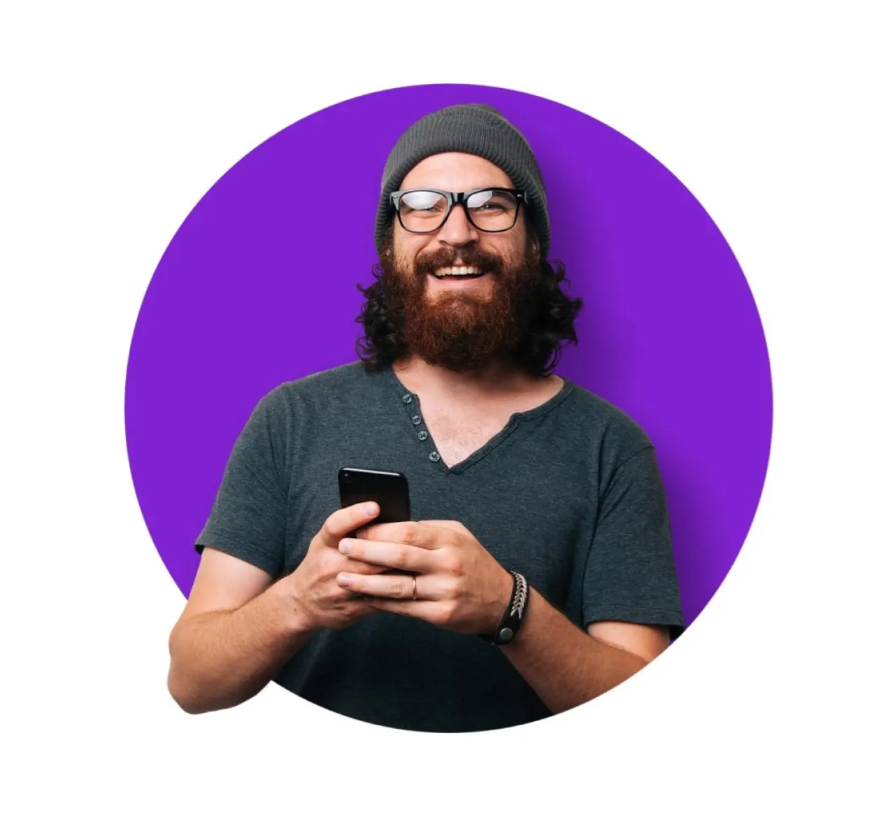 Bearded man wearing glasses and a beanie smiling while using a smartphone against a purple background.