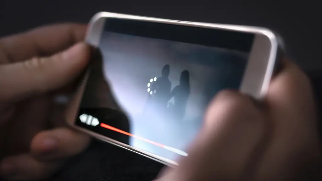 Lifestyle image closeup of hands holding a phone screen with a loading video displayed