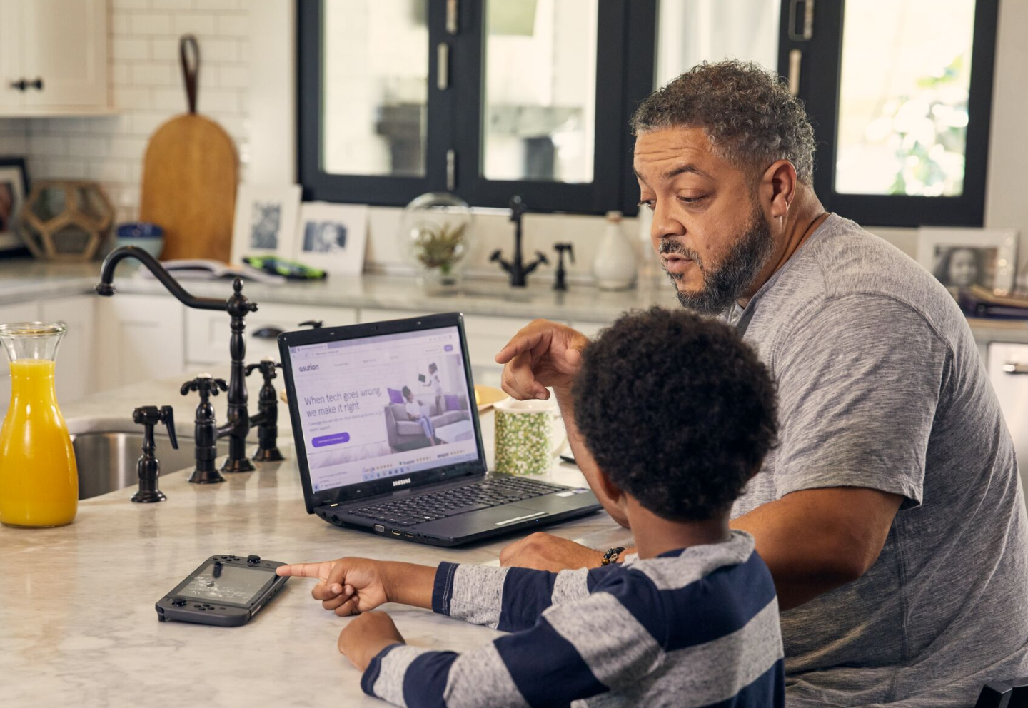 Man and child using a laptop on a kitchen counter