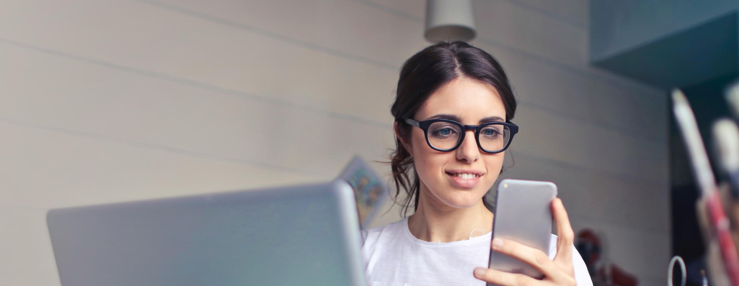 Woman using phone and laptop in creative office