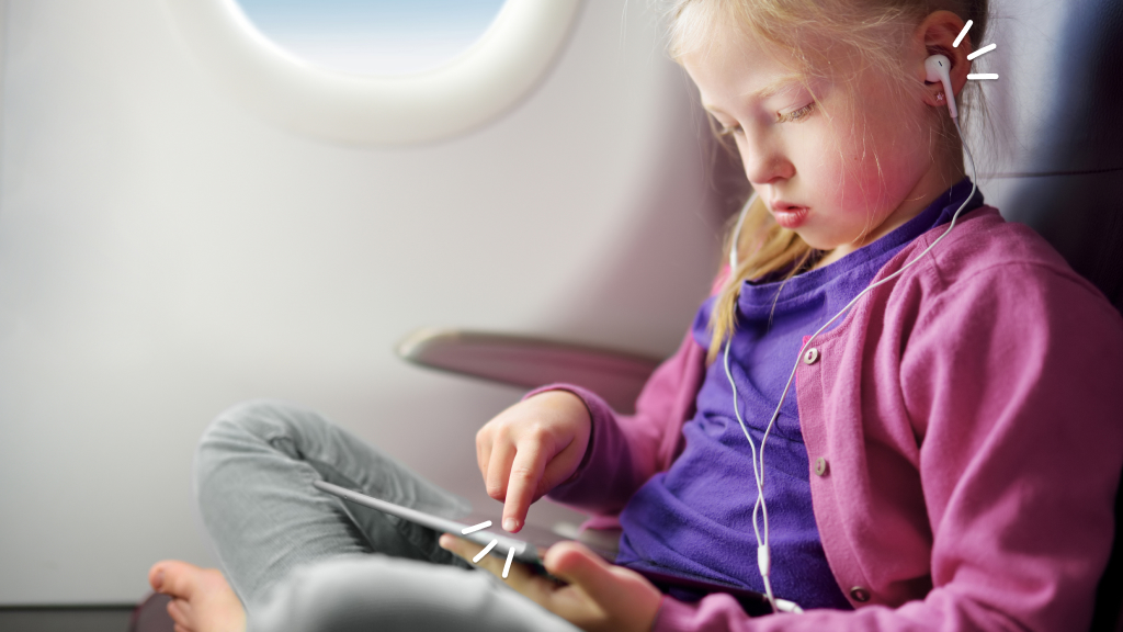 Child on airplane listening to headphone and playing on tablet