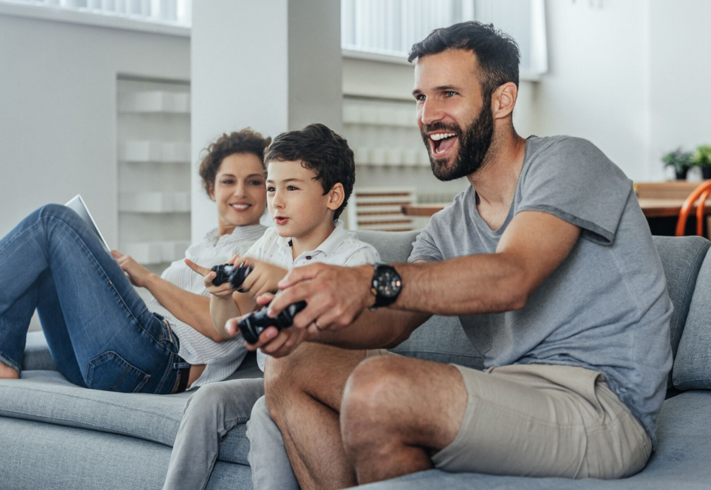 Father and son playing video games while mom watches