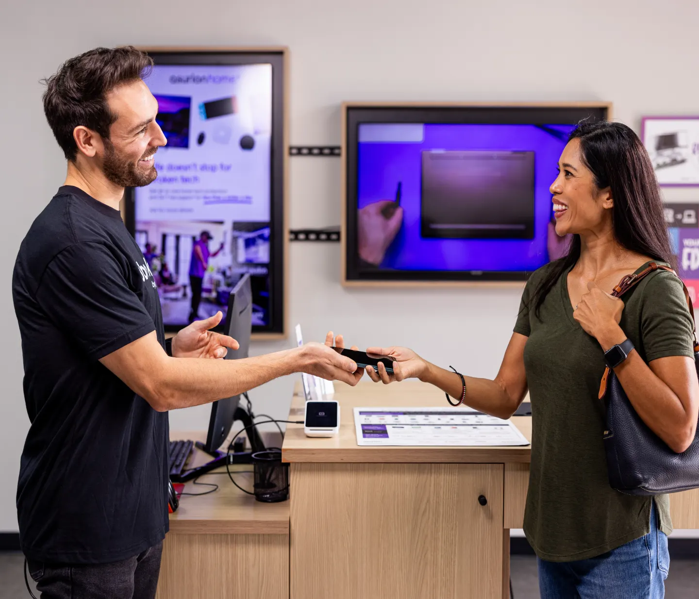 Customer in store handing a phone to an employee