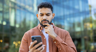 Thoughtful man looking at smartphone