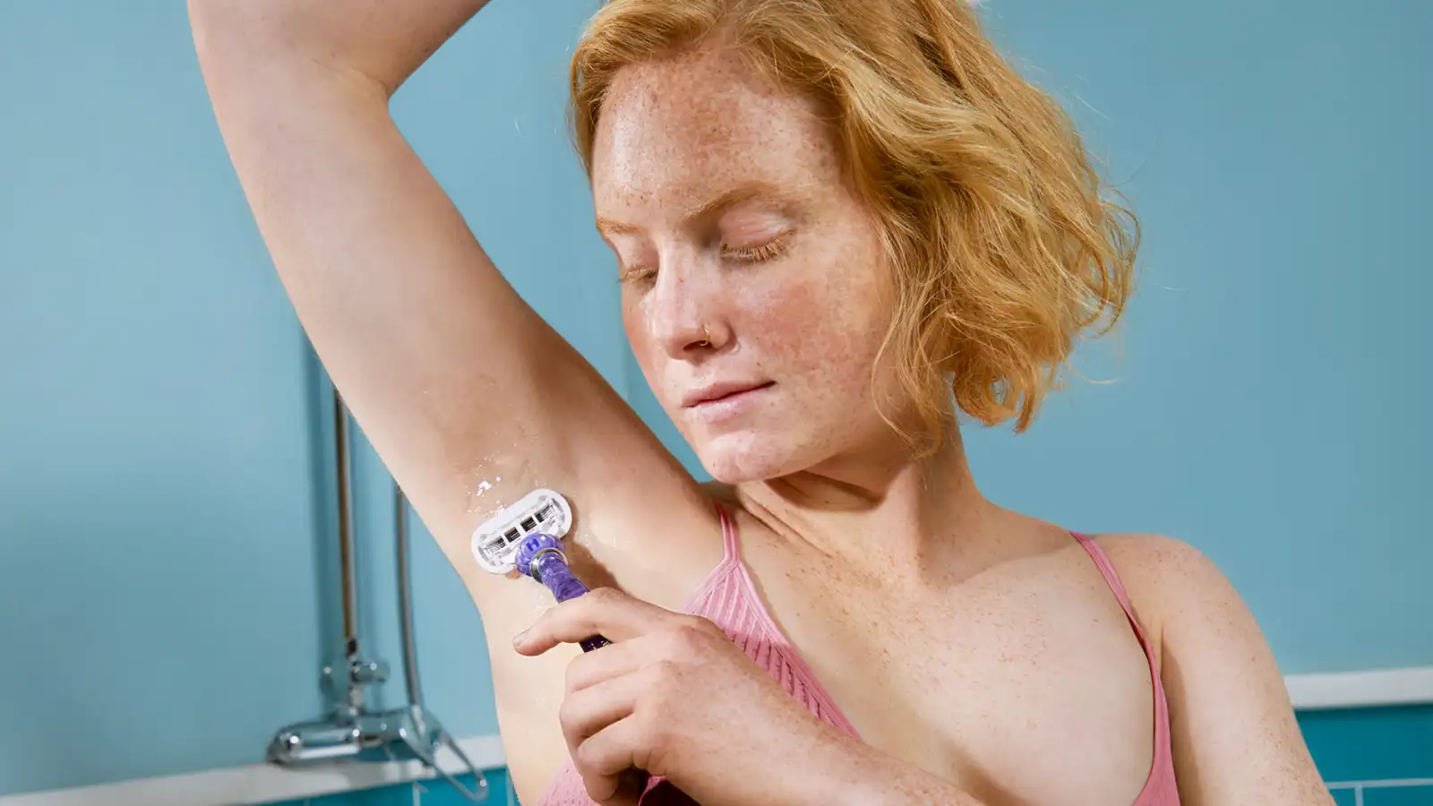 Blonde woman shaving her underarm