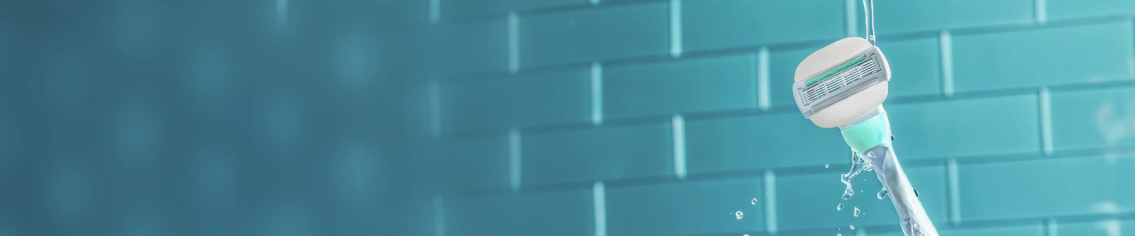 Venus razor blade with water droplets against a blue tiled background