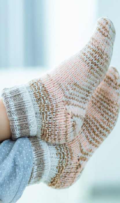 Legs hanging from the couch with thick, wooly winter socks on them