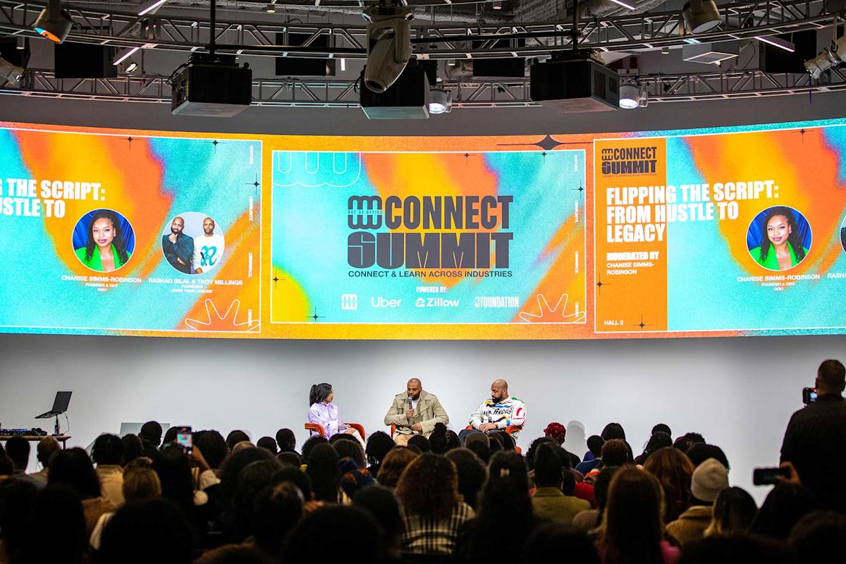 A large audience watches three speakers seated on a stage during the Connect Summit event. Bright, colorful screens behind them display the panel title "Flipping the Script: From Hustle to Legacy" and event branding.