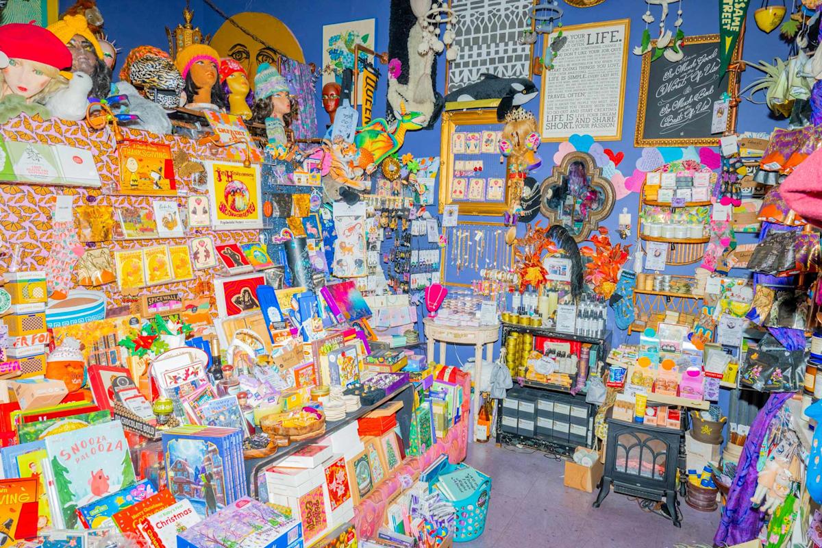 Bliss Vintage & Handmade, a colorful, crowded shop filled with assorted books, toys, hats, trinkets, decorations, and various gift items displayed on shelves.